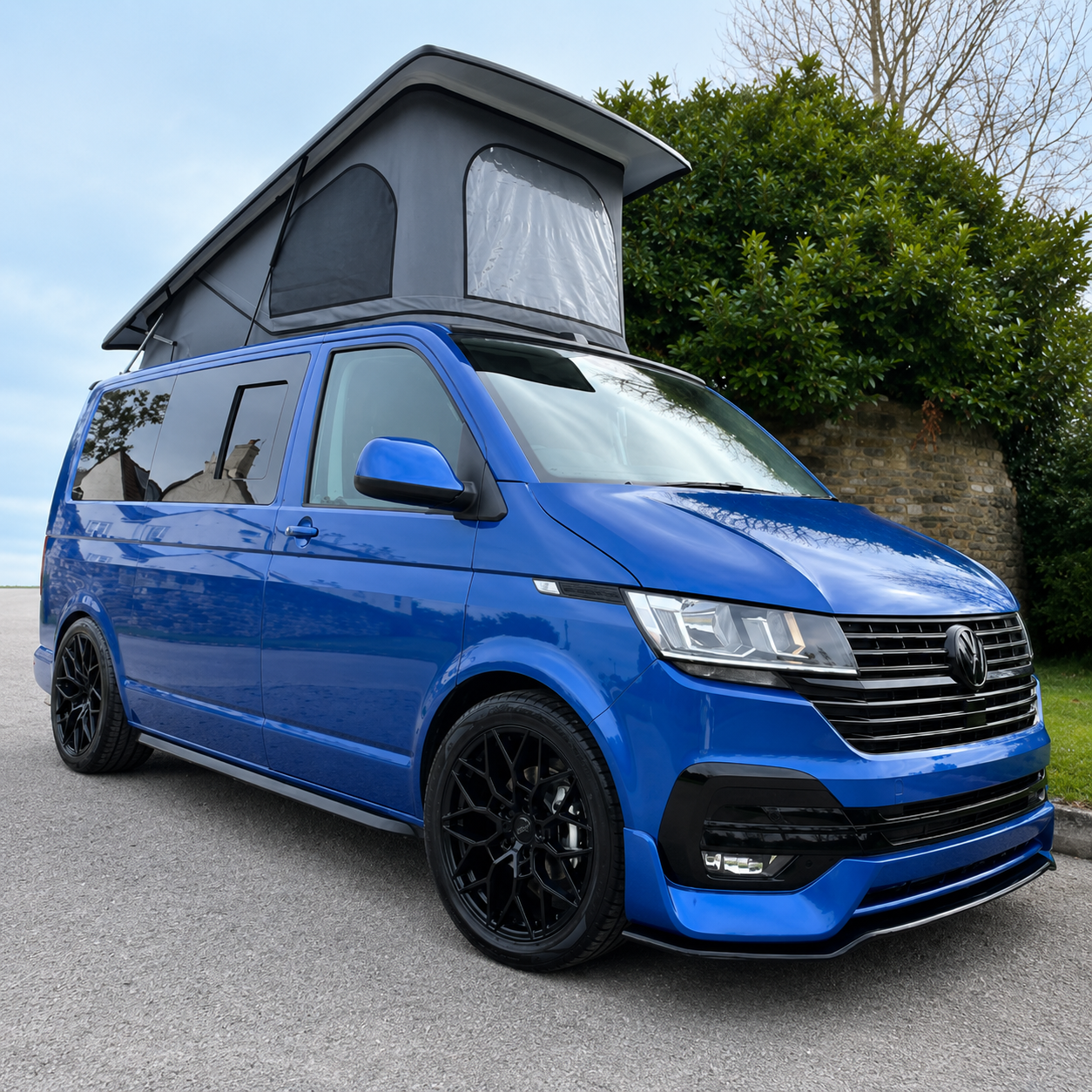 Blue VW Transporter campervan with a grey pop-top roof raised
