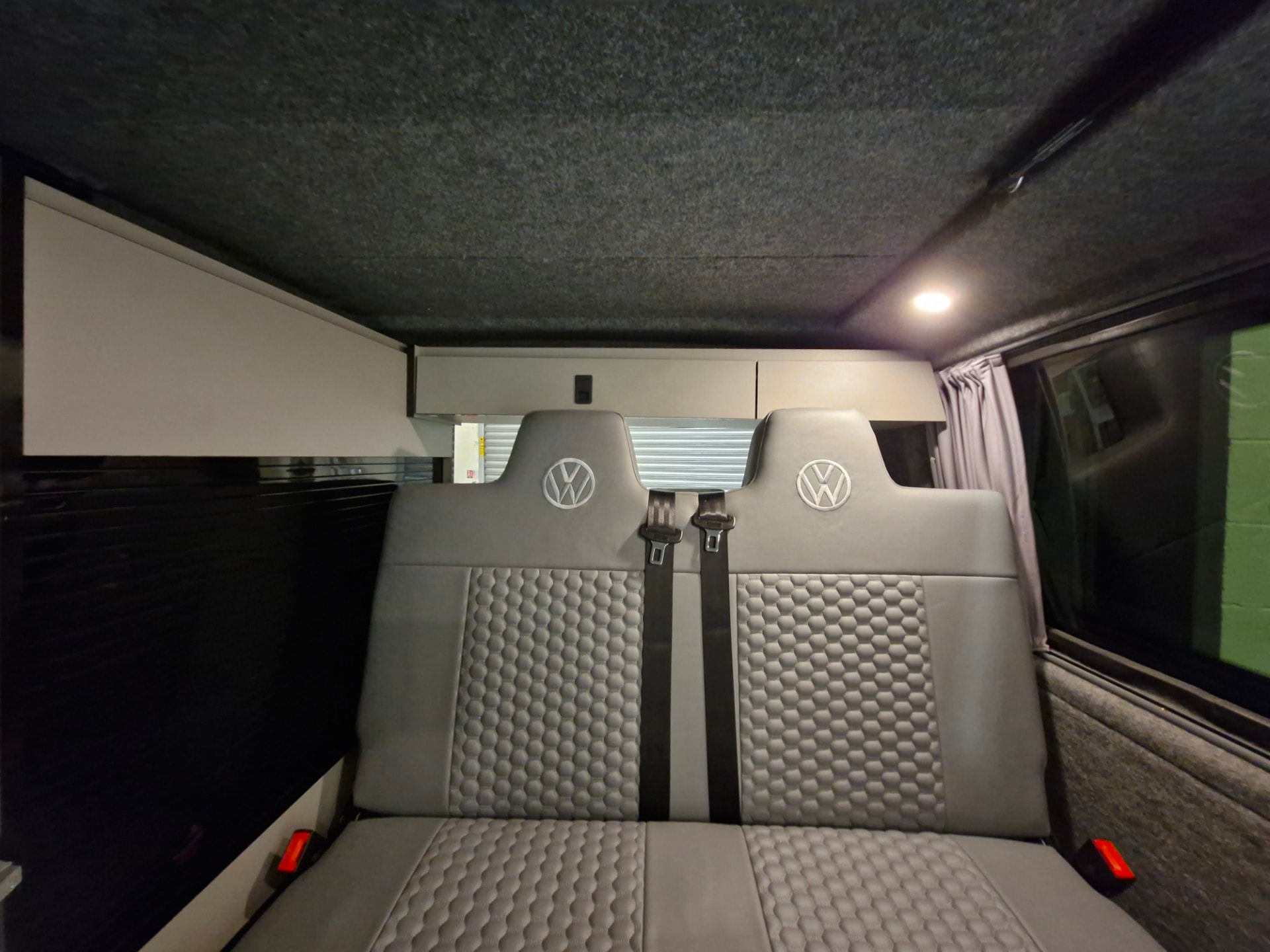 Rock and roll bed upright in its seating position with three-point belts and VW-embossed headrests