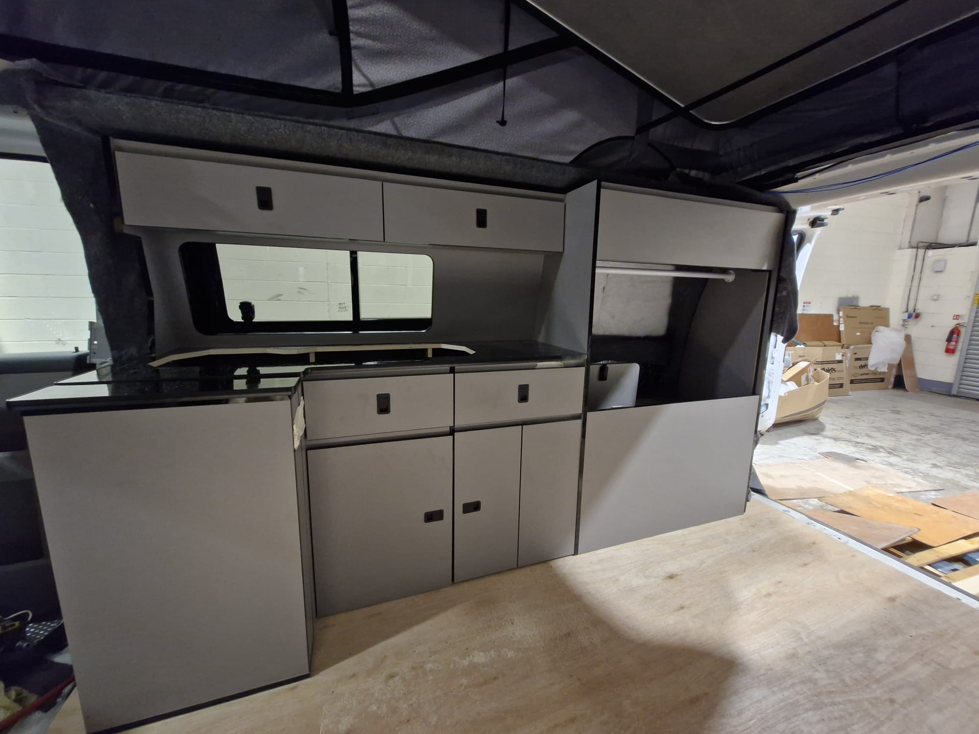 Full-width campervan kitchen furniture with overhead lockers, cupboards and worktop in a workshop build