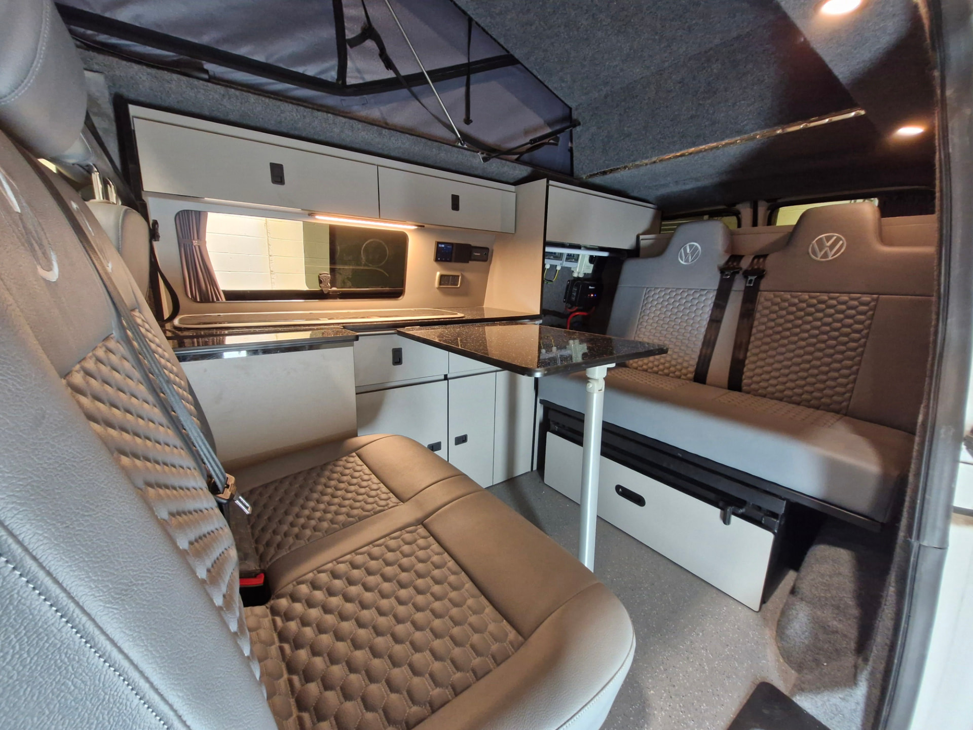 Finished VW Transporter camper interior with kitchen, rock and roll bed, table and pop-top roof raised