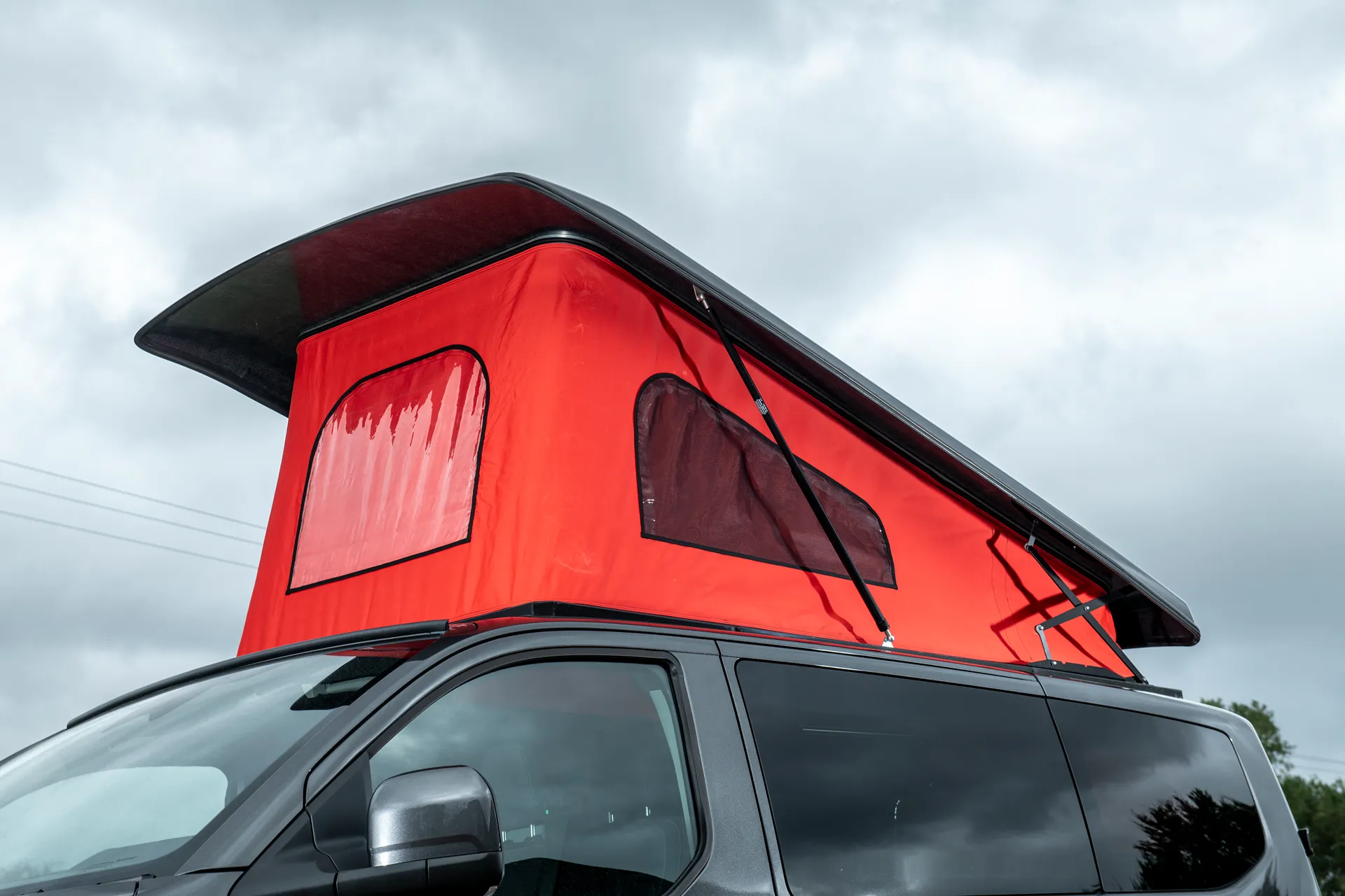 Austops pop-top roof raised on a grey VW Transporter with red canvas and mesh windows