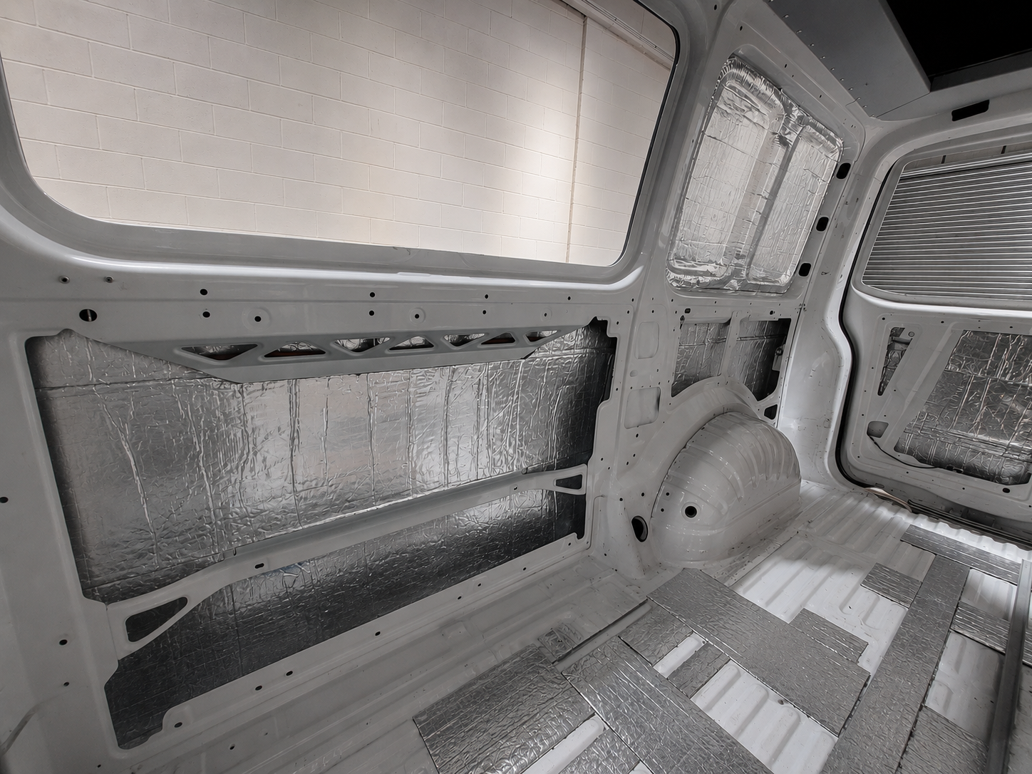 Sound deadening and thermal insulation fitted to the side panels and wheel arch of a van in the workshop