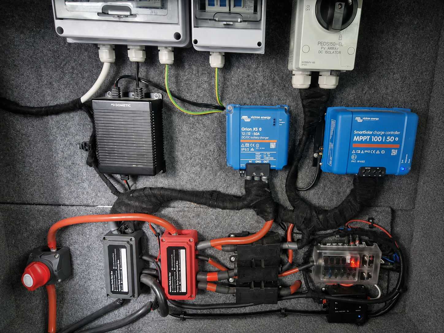 DC-DC charger, MPPT solar controller, busbars, fusing and consumer units laid out in a campervan